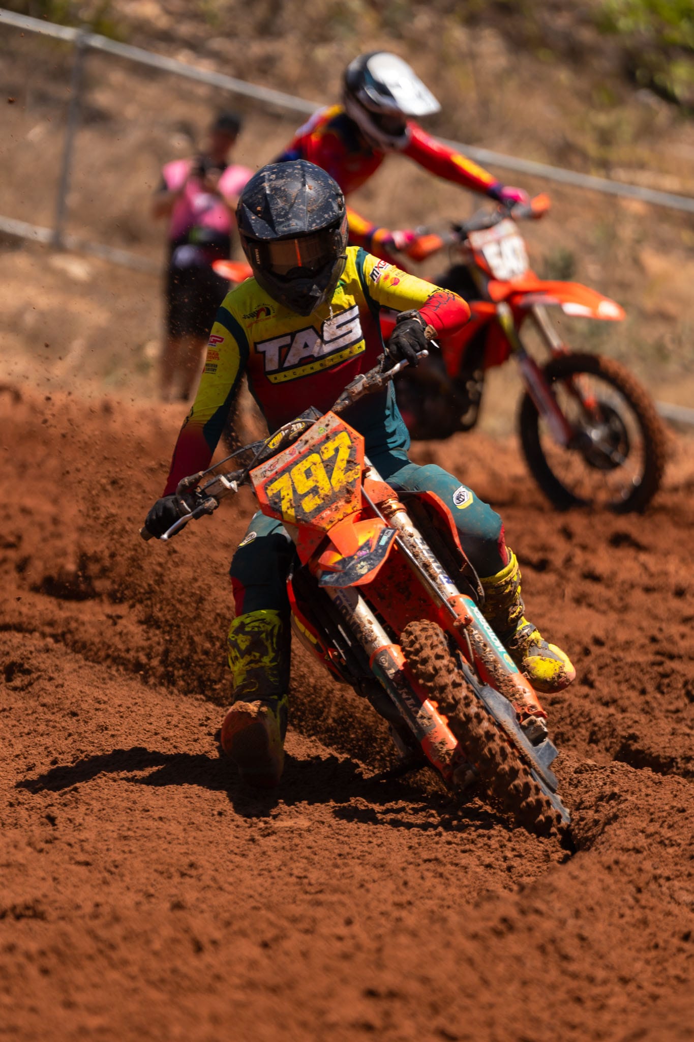 Motocross rider number 792 leans into a red dirt corner with another rider close behind at MXGP of Australia.