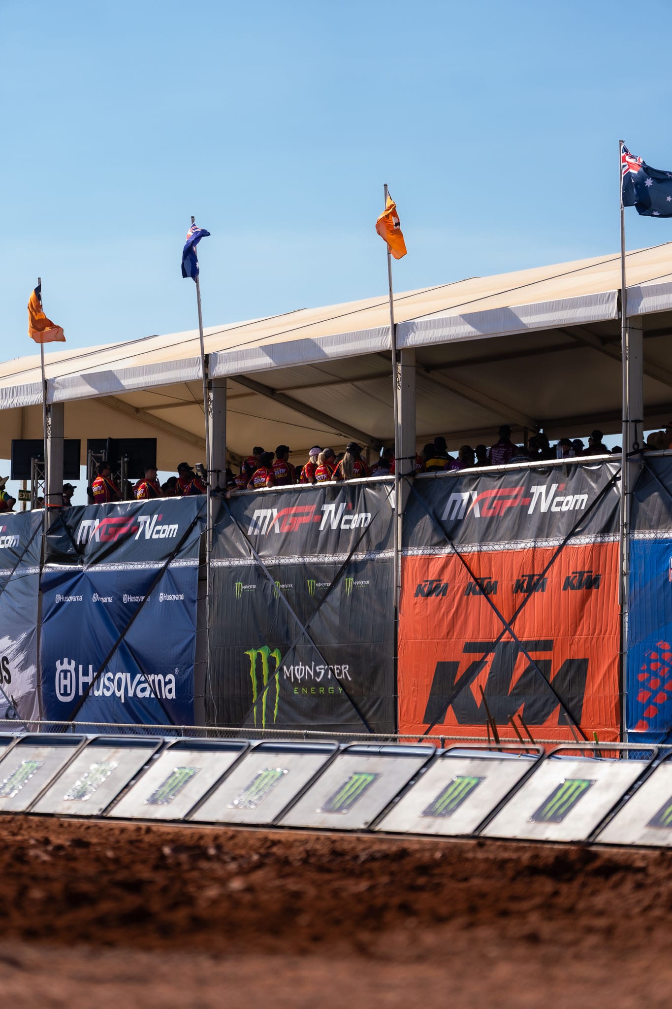 Spectators and event staff inside a covered viewing structure beside the MXGP of Australia motocross track at Hidden Valley.