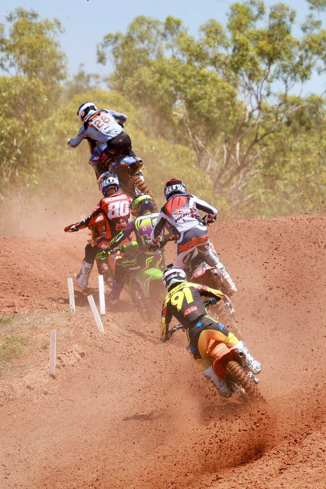 Five motocross riders race closely together through a dusty red dirt section of the track at MXGP Australia.