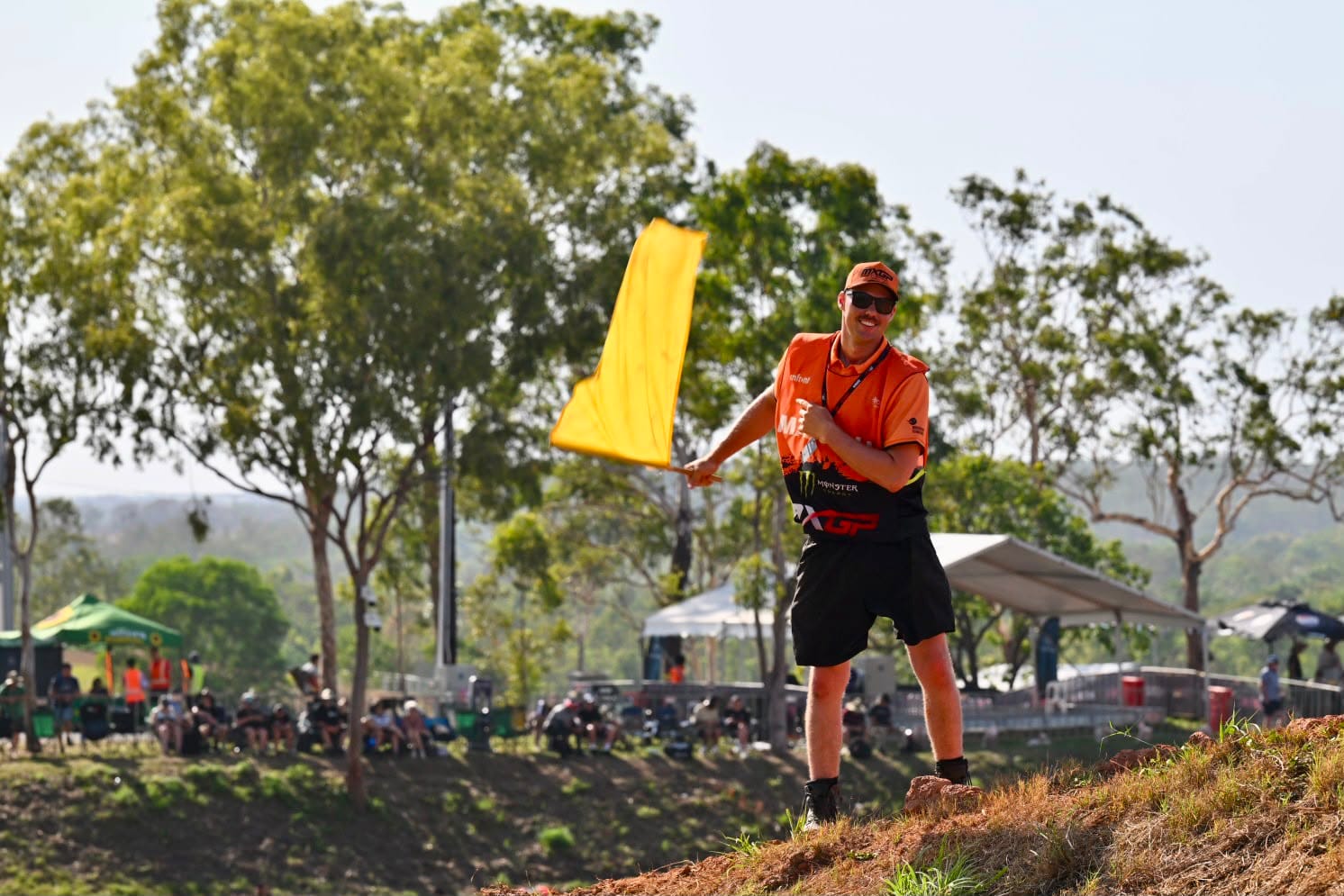 MXGP marshal stands beside the track waving a yellow caution flag during racing at Hidden Valley in Darwin.