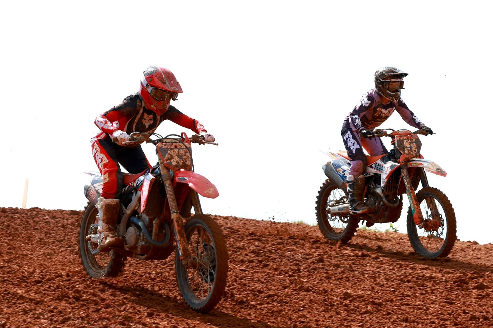 Two mud-covered motocross riders race across the red dirt track during MXGP Australia in Darwin.