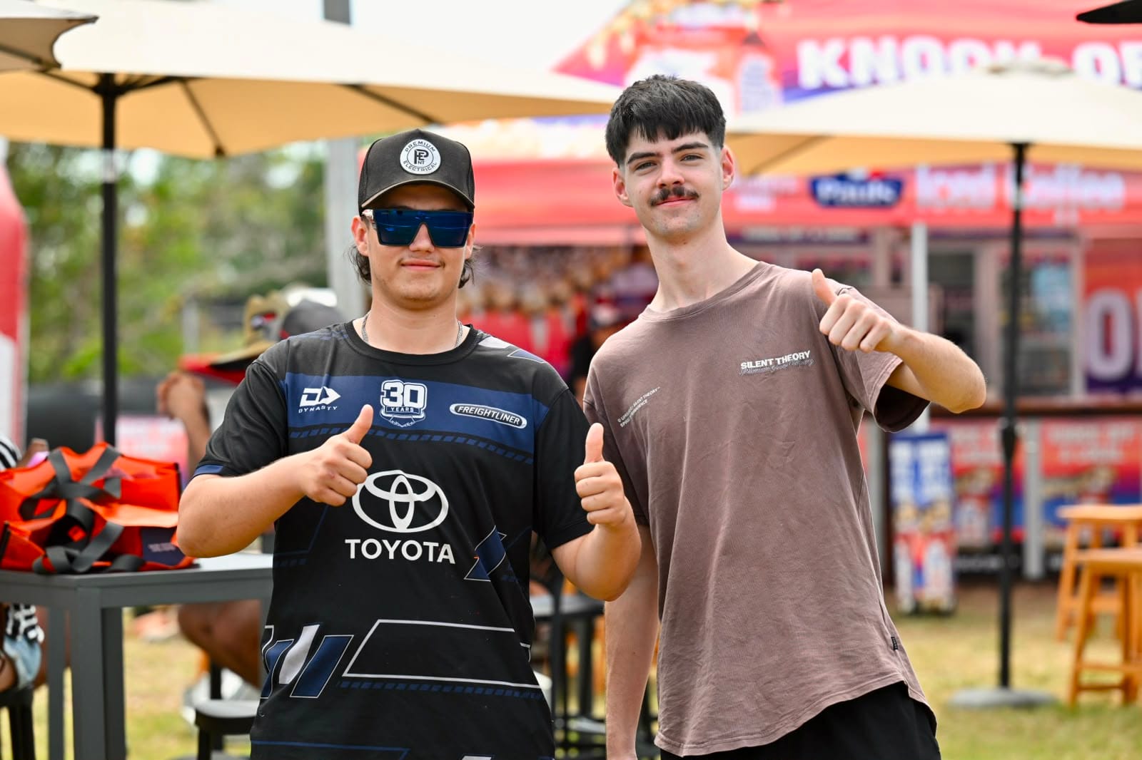 Two young spectators smile and give thumbs up in the fan area at MXGP Australia.
