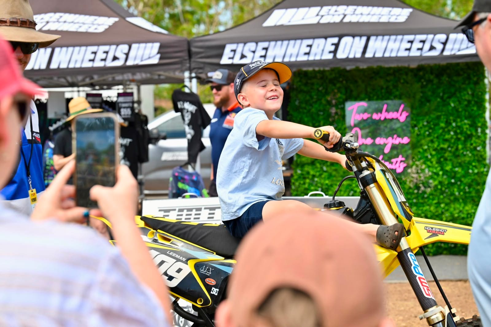 Young boy smiles while sitting on a motocross bike in the fan area at MXGP Australia in Darwin.