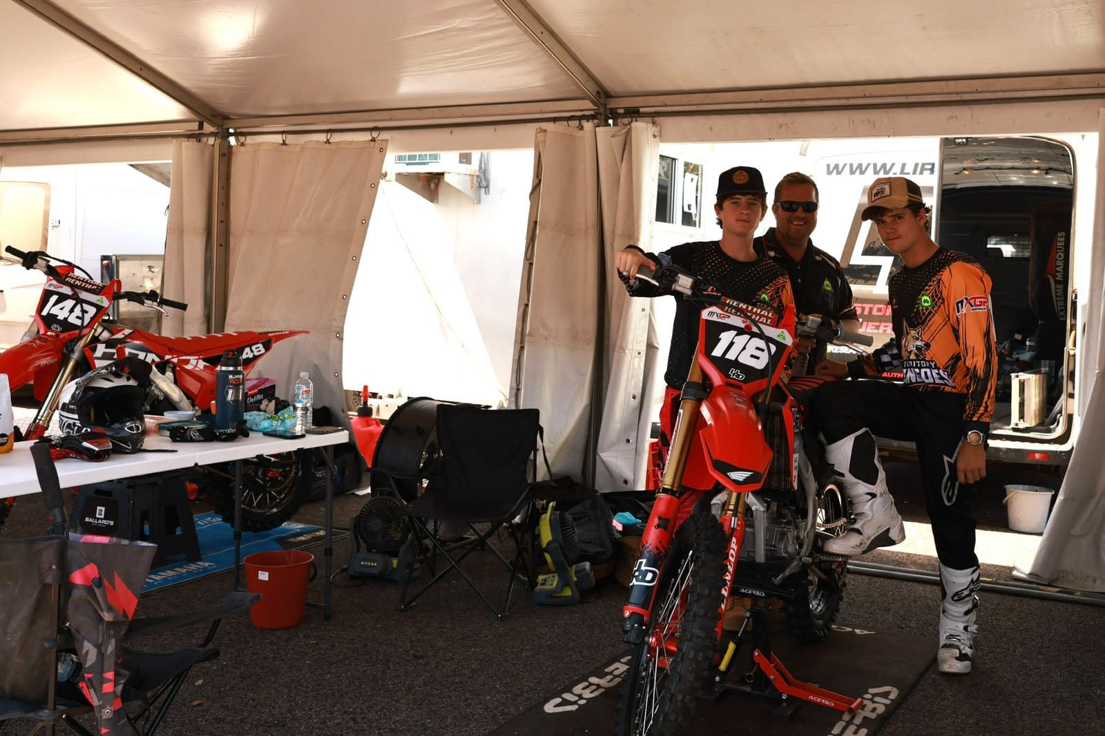Motocross riders and team members posing with a race bike inside a paddock tent at MXGP of Australia.