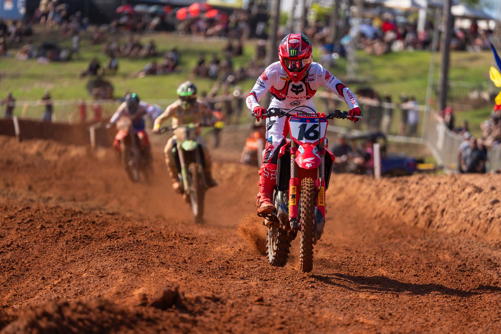 Motocross rider wearing number 16 races along the red dirt track with several riders following behind at MXGP Australia in Darwin.